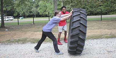 female student flipping over a large tire