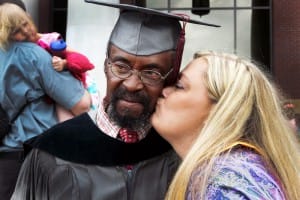 Roy Harness, left, poses for a photo following commencement exercises at Cain-Cochran Hall May 15. Harness, of Jackson, earned an Associate’s of Arts in drafting and design and plans to pursue a bachelor’s from Jackson State University. Pictured giving Harness a celebratory kiss is Barbara Cheney, right.