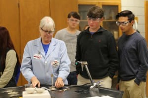 Hinds Community College chemistry instructor Lou Ann Williams sets up a science demonstration while Copiah Academy seniors Caleb Phillips and Noah Chapa, both of Crystal Springs, watch.