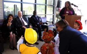 Dr. Mary Ann Greene, seated at left, interacts with children from the Early Childhood Education Technology program at Hinds Community College Jackson Campus-Academic/Technical Center during a program March 31 to name the program's building in her honor. Also seated are Hinds President Dr. Clyde Muse, center, and JATC Dean Leroy Levy. At the podium is Dr. Ericka Davis, who succeeded Greene as program director. Standing with the children is Carolyn Watkins, an assistant in the Early Childhood Education Laboratory. (Hinds Community College/Tammi Bowles)