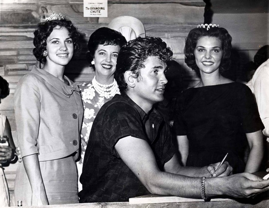 old black and white photo of young man with three young women behind him