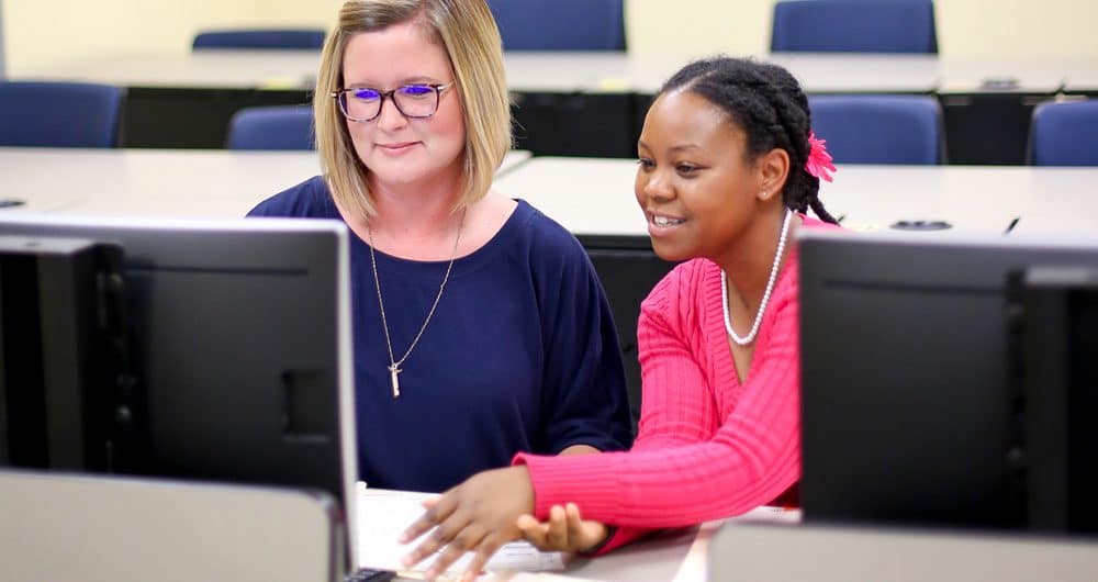 female instructor and student working on computer together