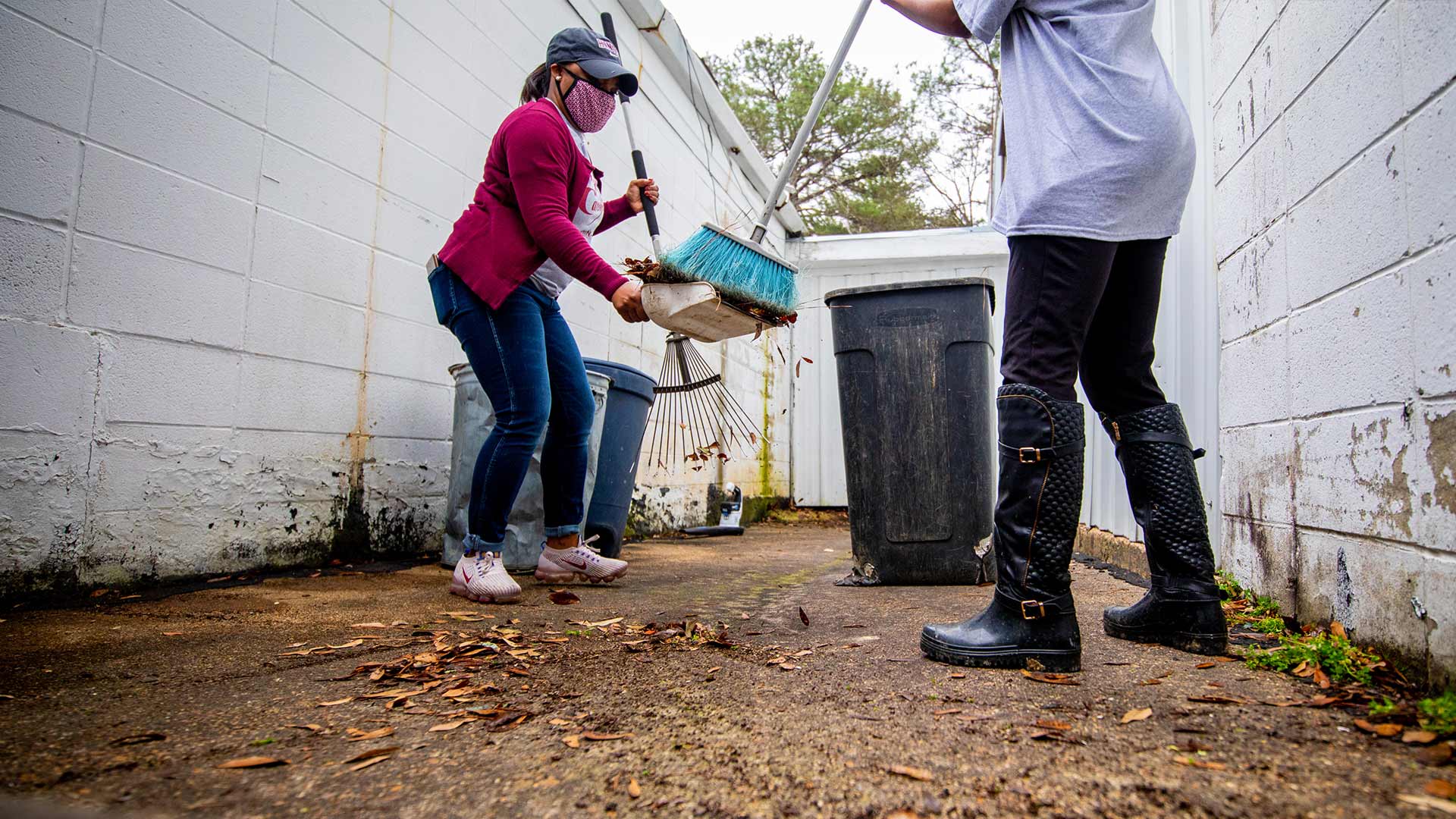 Christy Laster, left, and Cassandra Ellis work together to clear an area of leaves and pine needles.