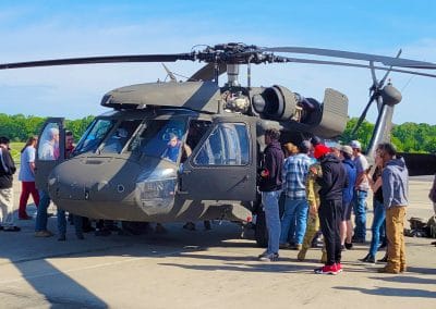 Group of aviation maintenance students gathered around a black hawk helicopter on the runway